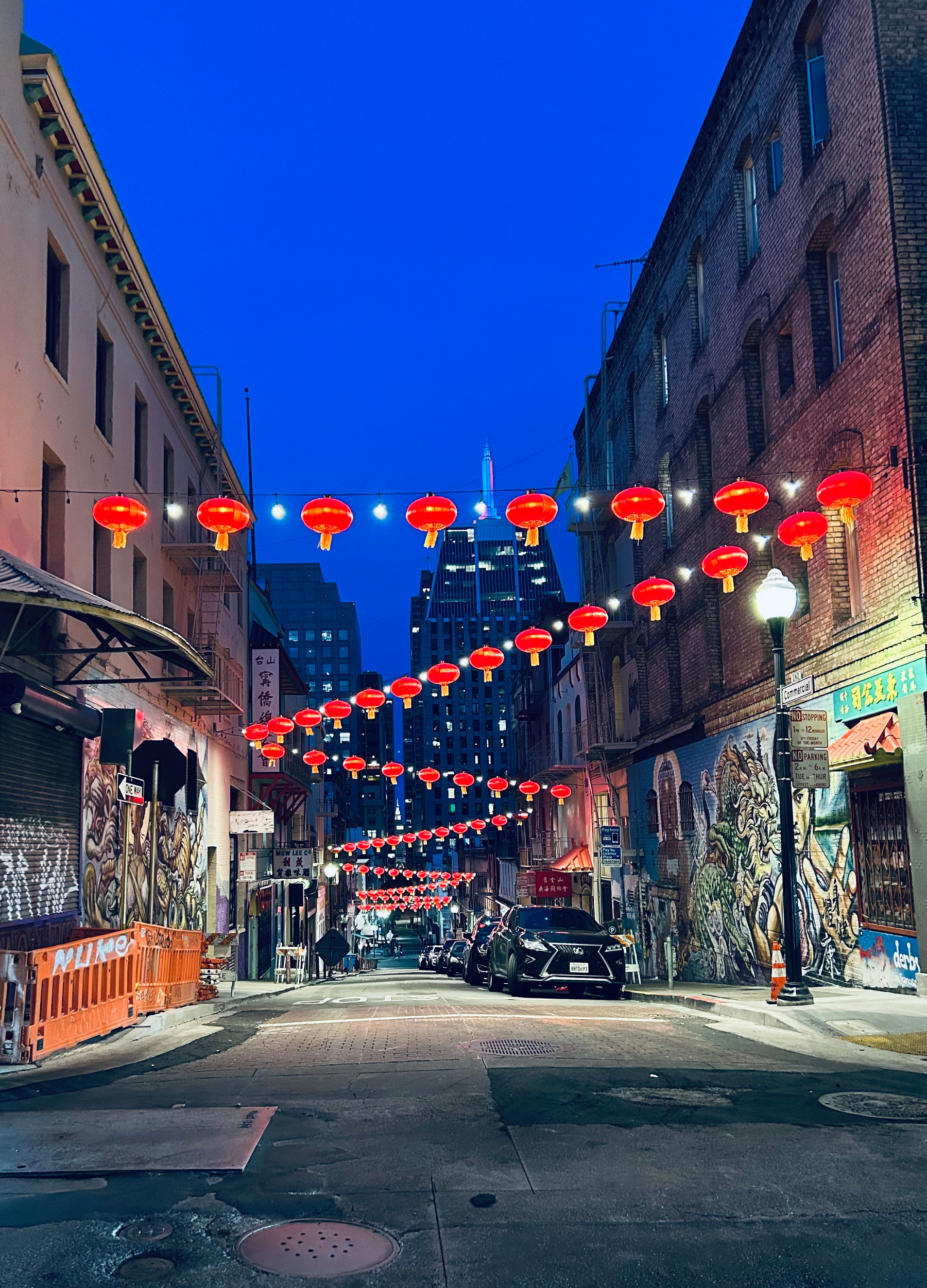 A picture from Chinatown at night, an alley with some neat red lanterns strung across it 
