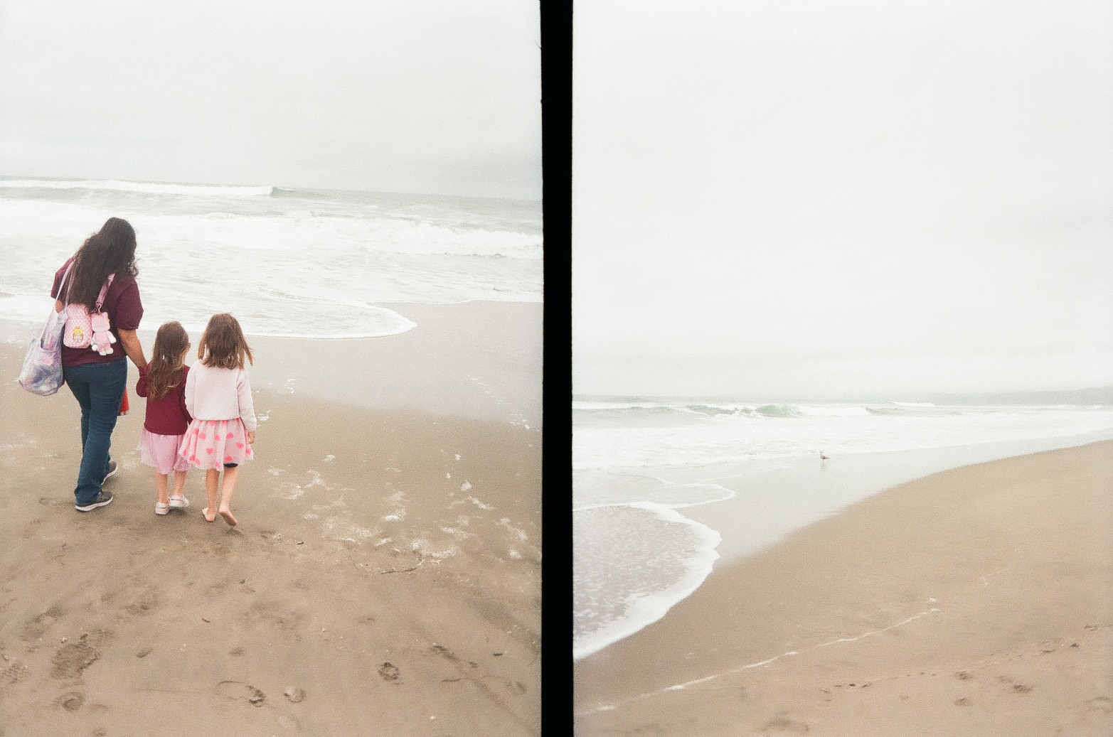 A woman and two children walk hand-in-hand along a foggy beach, leaving footprints in the sand.