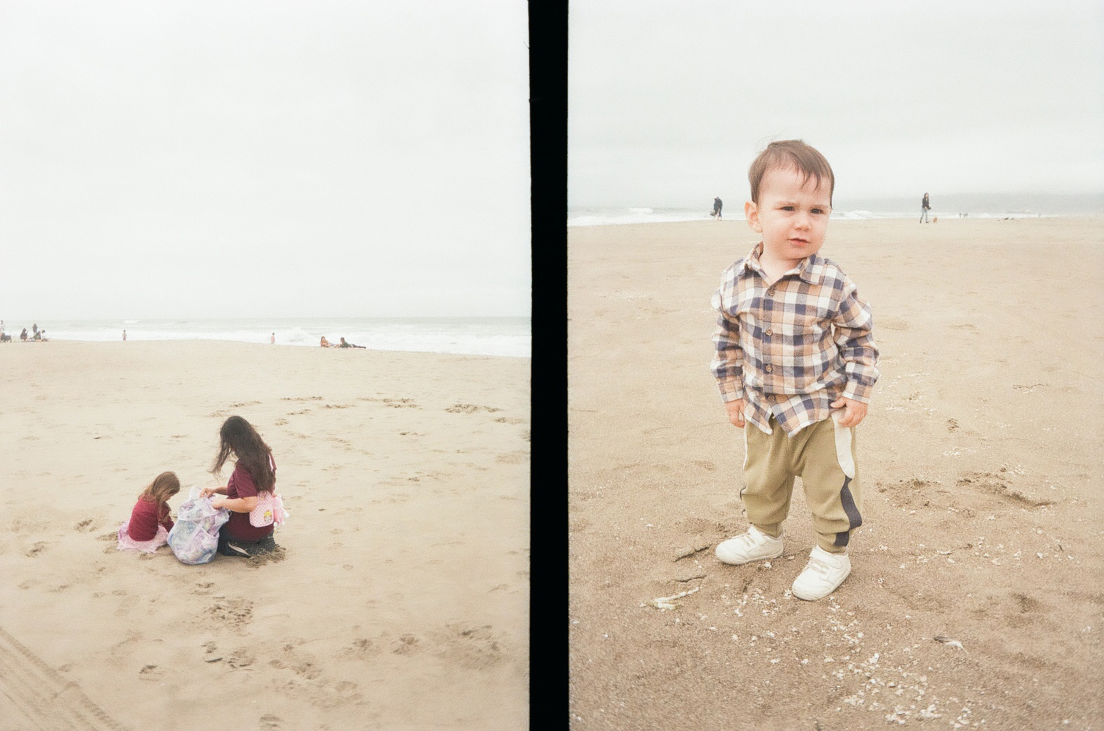 On a sandy beach, three people are sitting together on the left side while a young boy stands with his hands in his pockets on the right side.