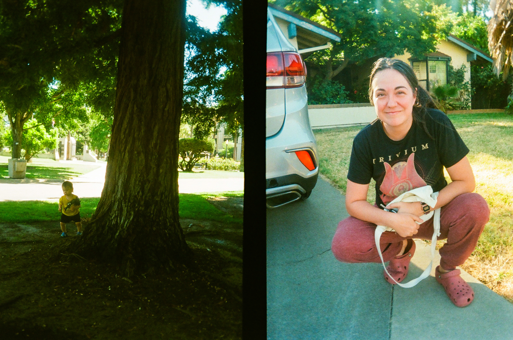 A child stands in the shade near a large tree on the left side, while a woman crouches smiling with a small dog on a leash on the right side in a sunny driveway.